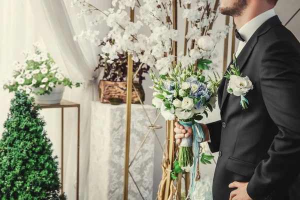 Groom holding bouquet in wedding hall — Stock Photo, Image