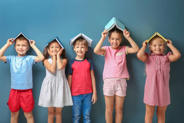 Милі маленькі діти з книгами на кольоровому фоні — стокове фото