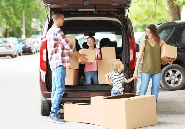 Familia feliz con cajas cerca del coche, al aire libre — Foto de Stock