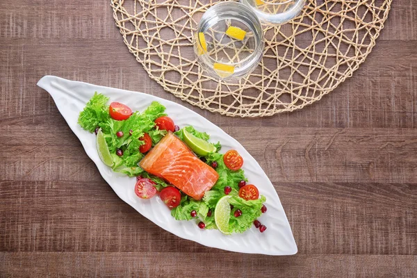 Placa con deliciosa ensalada de salmón en la mesa —  Fotos de Stock