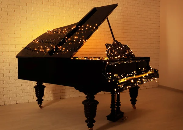 Piano with Christmas lights in empty room — Stock Photo, Image