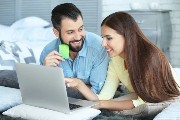 Young couple with laptop and credit card at home. Internet shopping concept