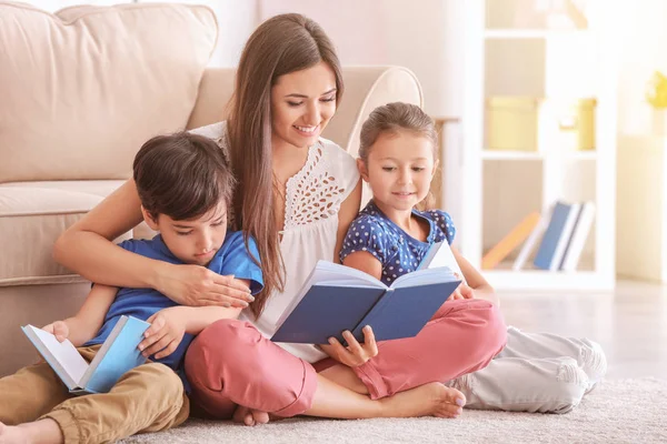 Jonge vrouw en haar lieve kinderen thuis boeken lezen — Stockfoto