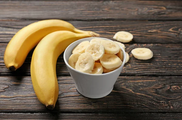 Bananas and bowl with slices — Stock Photo, Image