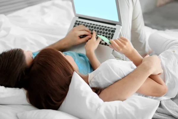 年轻夫妇的笔记本电脑躺在家里的床上。网络购物理念 — 图库照片