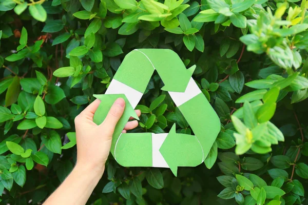 Mujer sosteniendo símbolo de reciclaje al aire libre — Foto de Stock