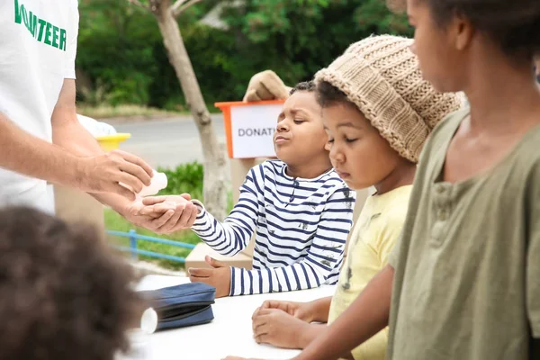 Voluntarios dando tabletas de vitaminas a niños africanos pobres al aire libre —  Fotos de Stock