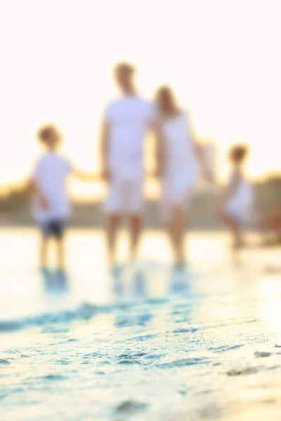 Vista borrosa de la familia feliz en la playa del mar —  Fotos de Stock