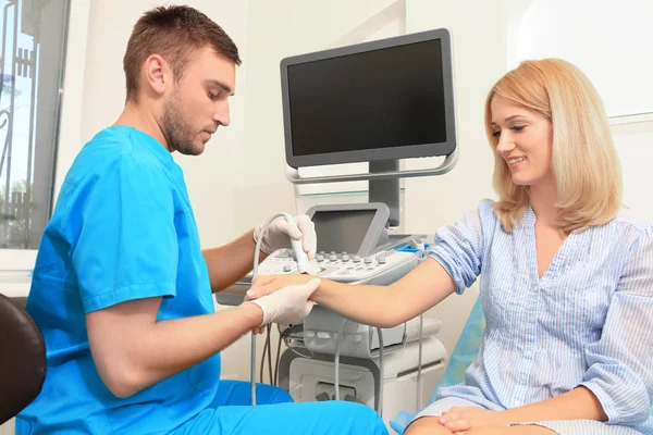 Medico che effettua un esame ecografico del polso del paziente in clinica — Foto Stock