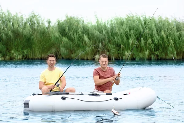 Dos hombres que pescan del barco inflable en río — Foto de Stock