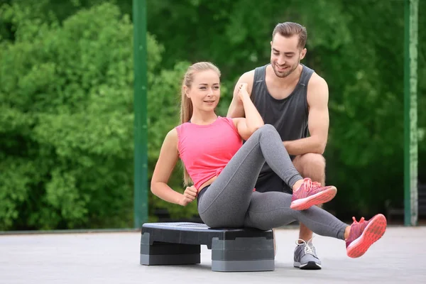 Mujer joven haciendo ejercicio con entrenador personal en el campo de deportes —  Fotos de Stock