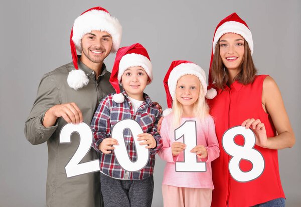 Happy family with paper figures 2018 on grey background. Christmas celebration concept