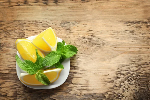 Plate with mint and lemon on wooden background — Stock Photo, Image