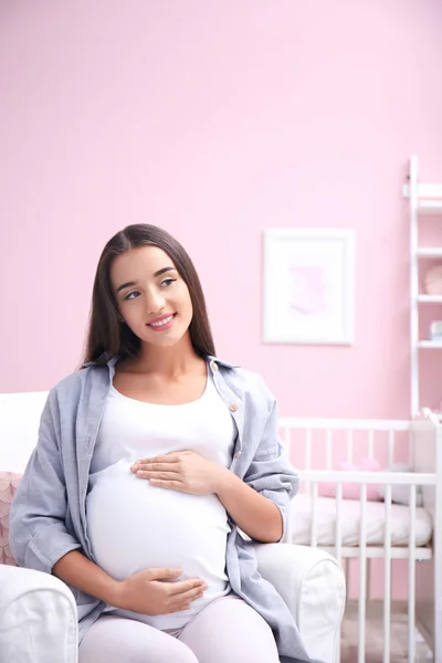 Wanita hamil duduk di kamar bayi — Stok Foto