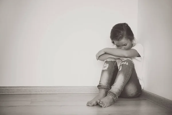 Little sad girl sitting on floor at home — Stock Photo, Image