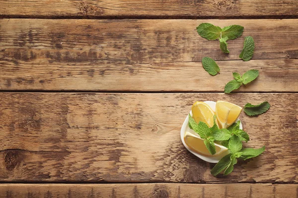 Plate with mint and lemon on wooden background — Stock Photo, Image