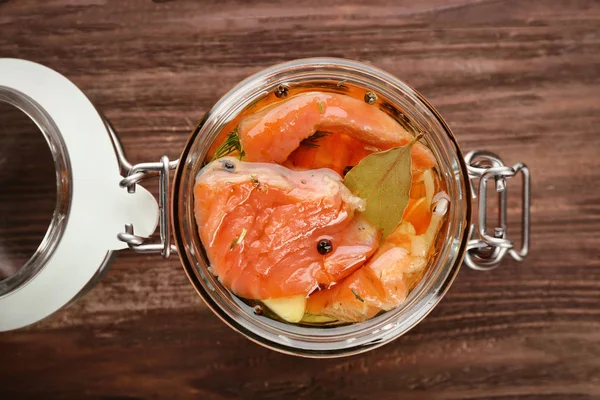 Jar with delicious marinated salmon on table — Stock Photo, Image