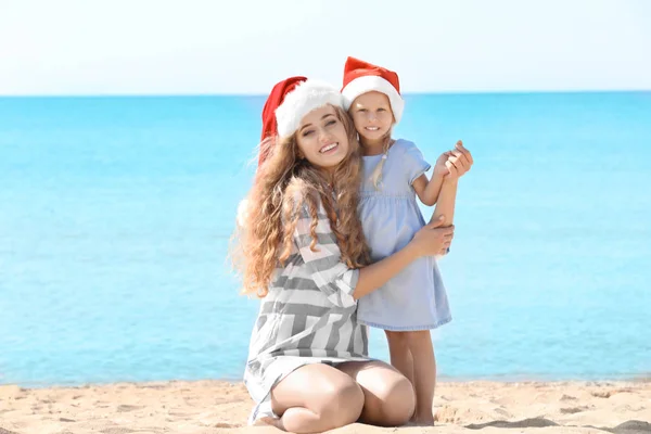 Jeune mère avec fille mignonne sur la plage. Concept de célébration de Noël — Photo