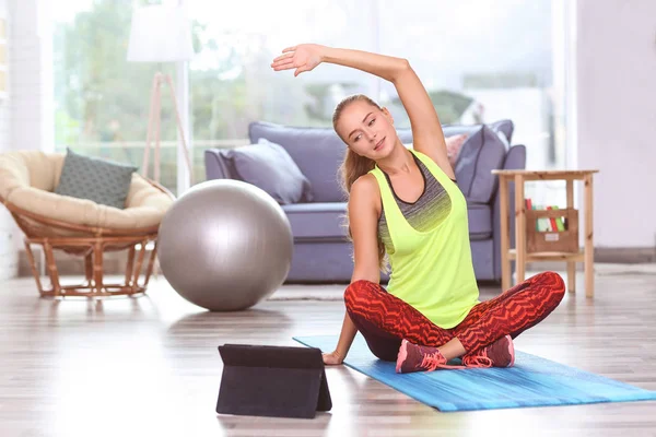 Joven deportista con tablet practicando yoga en casa —  Fotos de Stock