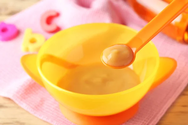Cuillère et bol en plastique avec nourriture pour bébé — Photo
