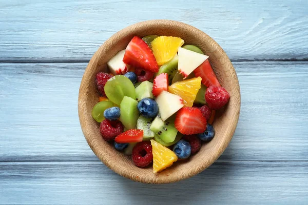 Tigela com deliciosa salada de frutas em fundo de madeira — Fotografia de Stock