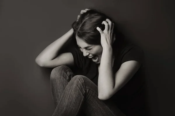 Jeune femme battue assise près du mur — Photo