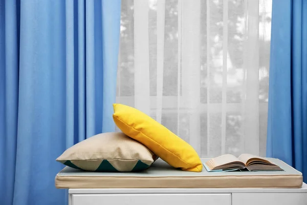 М'яка лавка з подушками біля красивих штор в приміщенні — стокове фото