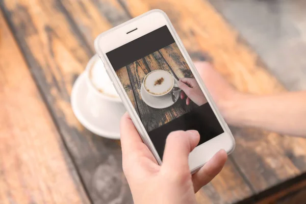 Mulher fotografando xícara de café com telefone celular — Fotografia de Stock