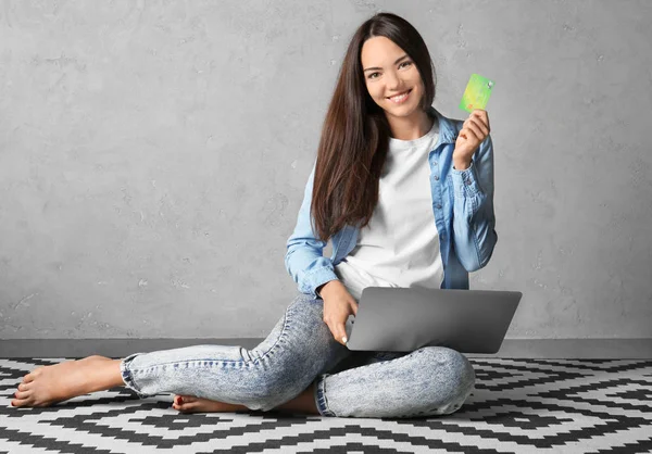 Jovem mulher usando laptop enquanto segurando cartão de crédito em casa. Conceito de compras na Internet — Fotografia de Stock