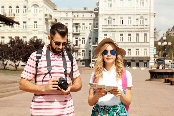 Glada unga turister med karta i vackra stad — Stockfoto