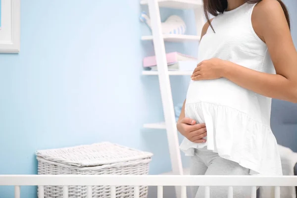 Mulher grávida em pé no quarto do bebê — Fotografia de Stock