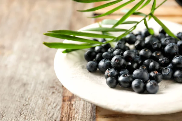 Plate with fresh acai berries on wooden table — Stock Photo, Image