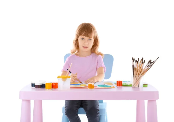 Талантливая девушка рисует, сидя за столом на белом фоне — стоковое фото