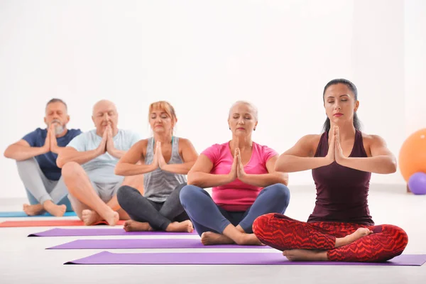 Gruppo di uomini e donne maturi a lezione di yoga al chiuso — Foto Stock