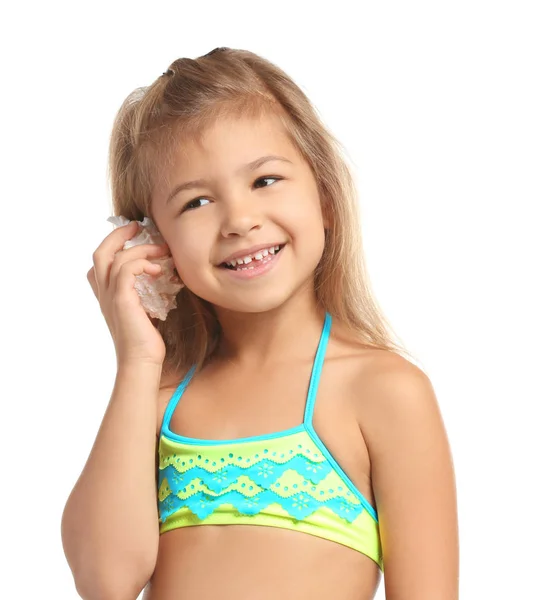 Adorable niña en traje de baño escuchando concha de mar sobre fondo blanco — Foto de Stock