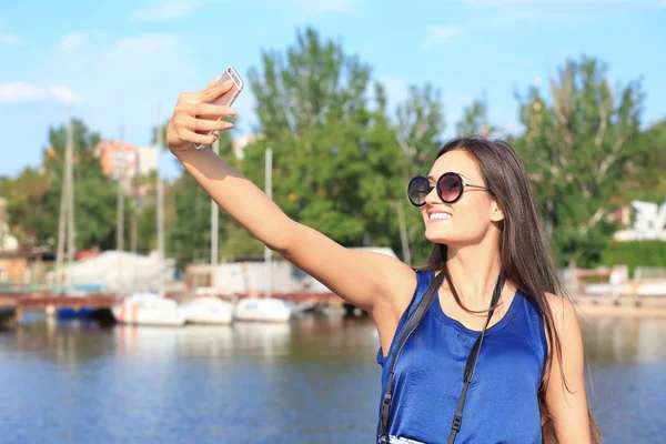 Krásné mladé turisty při selfie na břehu řeky — Stock fotografie