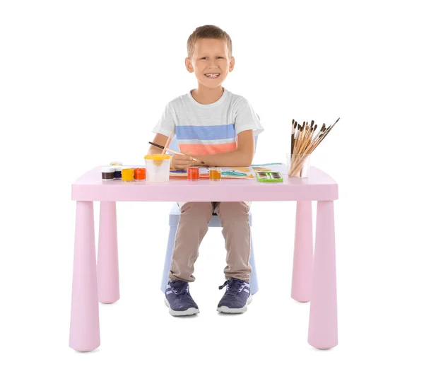 Talented boy painting while sitting at table against white background — Stock Photo, Image