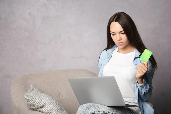 젊은 여자는 회색 바탕에 신용 카드를 들고 하는 동안 노트북을 사용 하 여. 인터넷 쇼핑 개념 — 스톡 사진