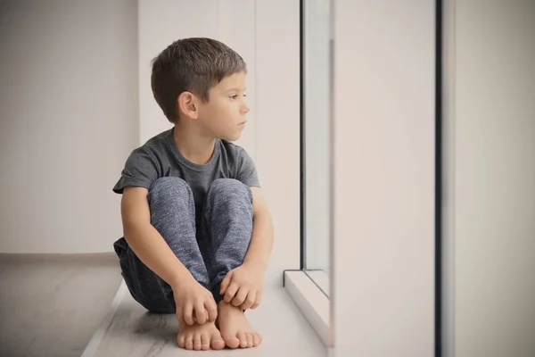 Сумний самотній хлопчик сидить на підвіконні вдома — стокове фото
