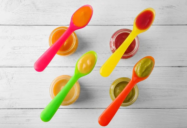 Plastic spoons and jars with baby food — Stock Photo, Image