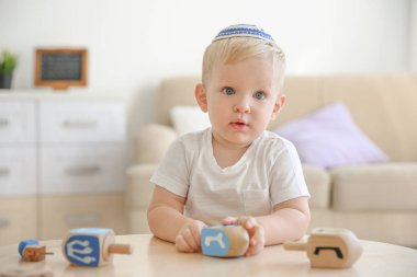Yahudi çocuk evde dreidel ile oynuyor.
