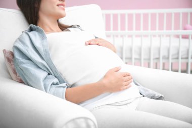 Hamile kadın bebeğin odasında oturuyordu