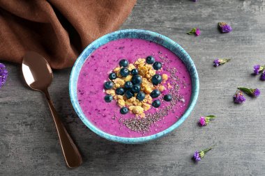 Acai güler yüzlü, çilek ve gri arka plan üzerine müsli kase