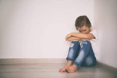 Köşede oturmuş korkmuş küçük bir kız. Aile içi şiddet kavramı