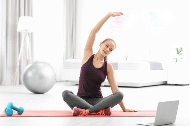 Evde yoga pratik laptop olan sportif kadın