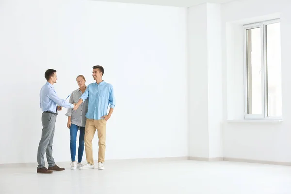 Hombre agente inmobiliario y joven pareja comprando piso nuevo — Foto de Stock
