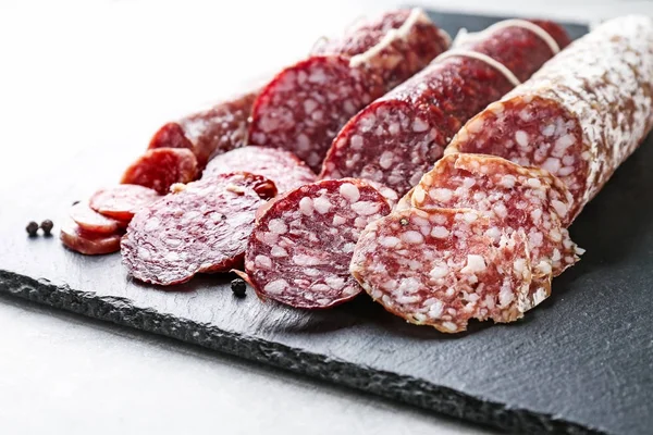 Delicious sliced sausages on slate plate — Stock Photo, Image