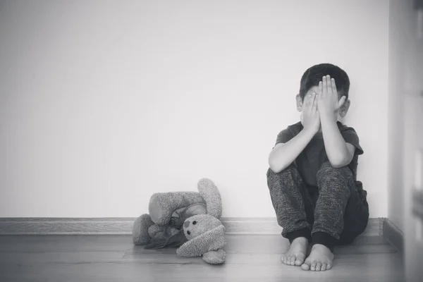 Little sad boy sitting on floor at home — Stock Photo, Image