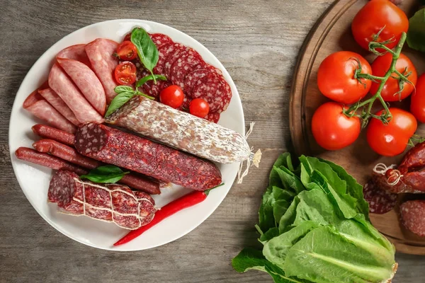 Placa con deliciosas salchichas en rodajas sobre mesa de madera — Foto de Stock