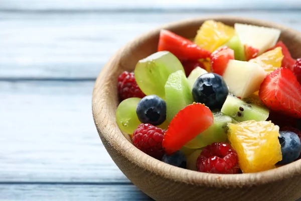 Tigela com deliciosa salada de frutas em fundo de madeira — Fotografia de Stock